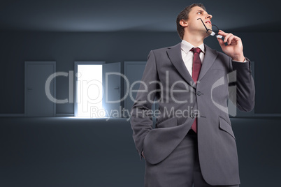 Composite image of thinking businessman holding his glasses