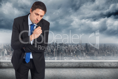 Composite image of thinking businessman holding pen