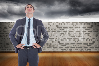 Composite image of smiling businessman with hands on hips