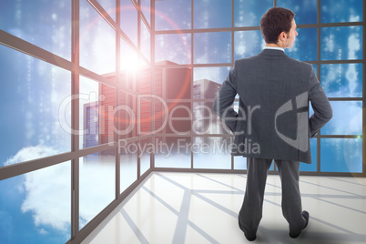 Composite image of businessman standing with hands on hips