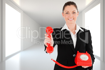 Composite image of charming woman in suit holding a red telephon