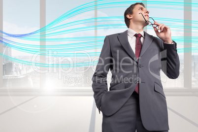 Composite image of thinking businessman holding his glasses