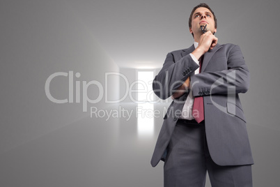 Composite image of thinking businessman holding his glasses