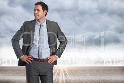 Composite image of smiling businessman with hands on hips