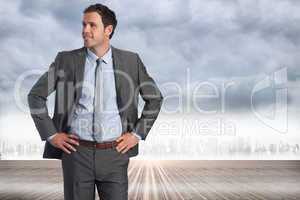 Composite image of smiling businessman with hands on hips