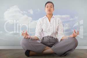 Composite image of businesswoman sitting in lotus pose