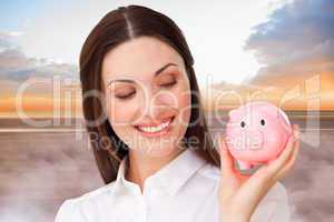 Composite image of confident businesswoman holding a piggybank