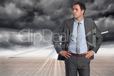 Composite image of serious businessman with hands on hips