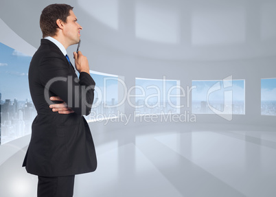 Composite image of thinking businessman holding pen