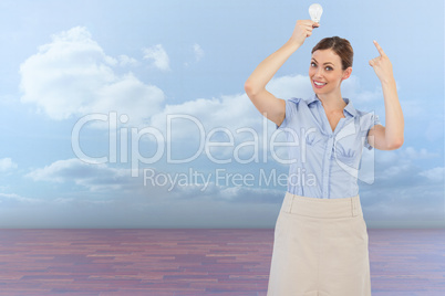 Composite image of classy businesswoman holding light bulb above