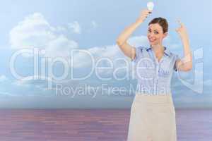Composite image of classy businesswoman holding light bulb above