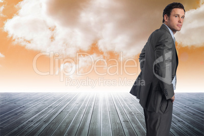 Composite image of serious businessman with hands on hips