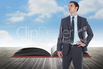 Composite image of serious businessman with hand on hip