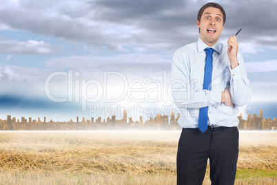 Composite image of thinking businessman holding pen