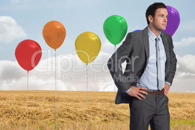 Composite image of serious businessman with hands on hips