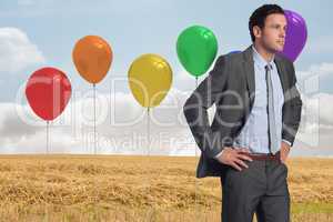 Composite image of serious businessman with hands on hips