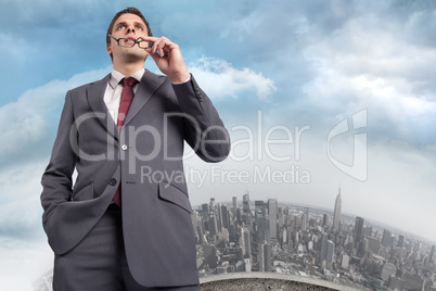 Composite image of thinking businessman holding his glasses