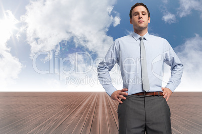 Composite image of serious businessman with hands on hips