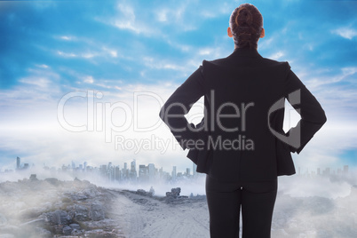 Composite image of businesswoman with hands on hips