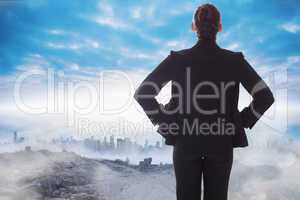 Composite image of businesswoman with hands on hips