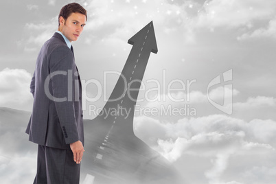 Composite image of serious businessman with hand on hip