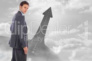 Composite image of serious businessman with hand on hip