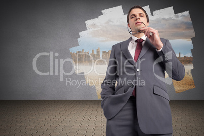 Composite image of thinking businessman holding his glasses