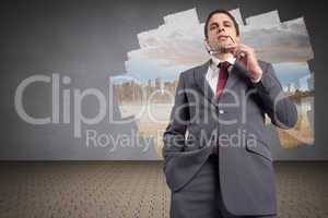 Composite image of thinking businessman holding his glasses