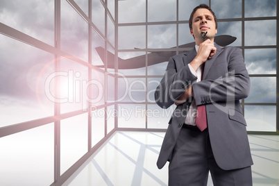 Composite image of thinking businessman holding his glasses