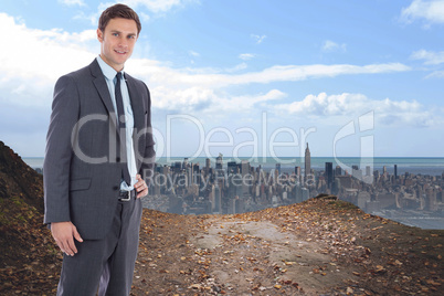 Composite image of smiling businessman with hand on hip