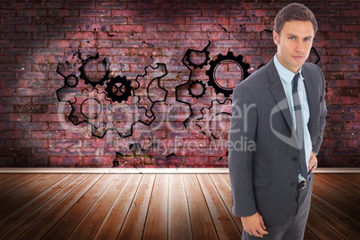 Composite image of serious businessman standing with hand on hip