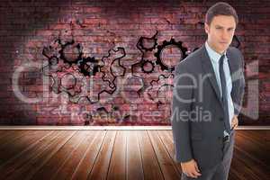 Composite image of serious businessman standing with hand on hip