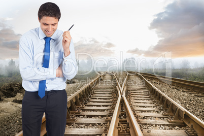 Composite image of thinking businessman holding pen