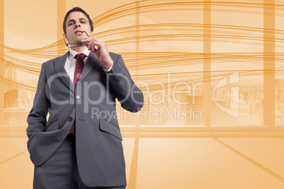 Composite image of thinking businessman holding his glasses