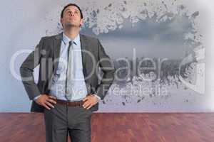 Composite image of serious businessman with hands on hips