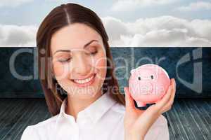 Composite image of confident businesswoman holding a piggybank