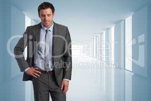 Composite image of smiling businessman with hand on hip