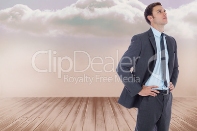 Composite image of serious businessman with hands on hips