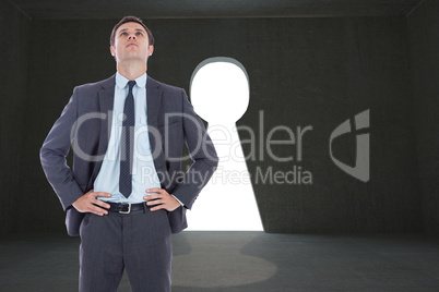 Composite image of serious businessman with hands on hips