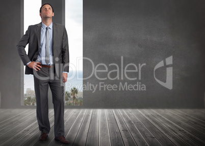 Composite image of serious businessman with hand on hip