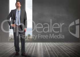 Composite image of serious businessman with hand on hip