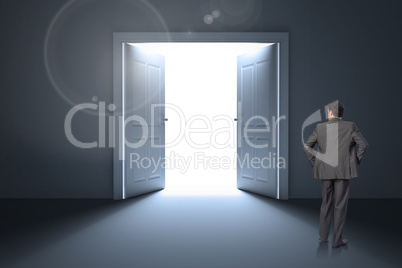 Composite image of businessman with hands on hips