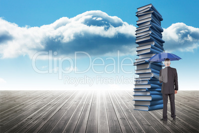 Composite image of businessman holding umbrella