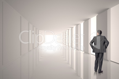 Composite image of businessman with hands on hips