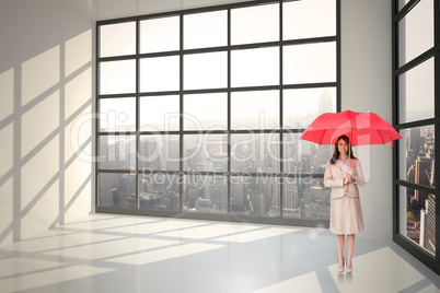 Composite image of attractive businesswoman holding red umbrella