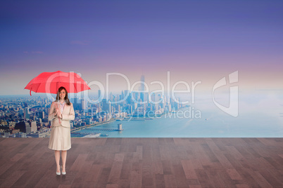 Composite image of attractive businesswoman holding red umbrella