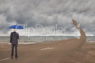 Composite image of businessman holding umbrella