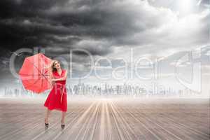 Composite image of elegant blonde holding umbrella