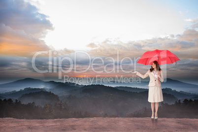 Composite image of attractive businesswoman holding red umbrella