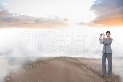 Composite image of businesswoman posing with binoculars